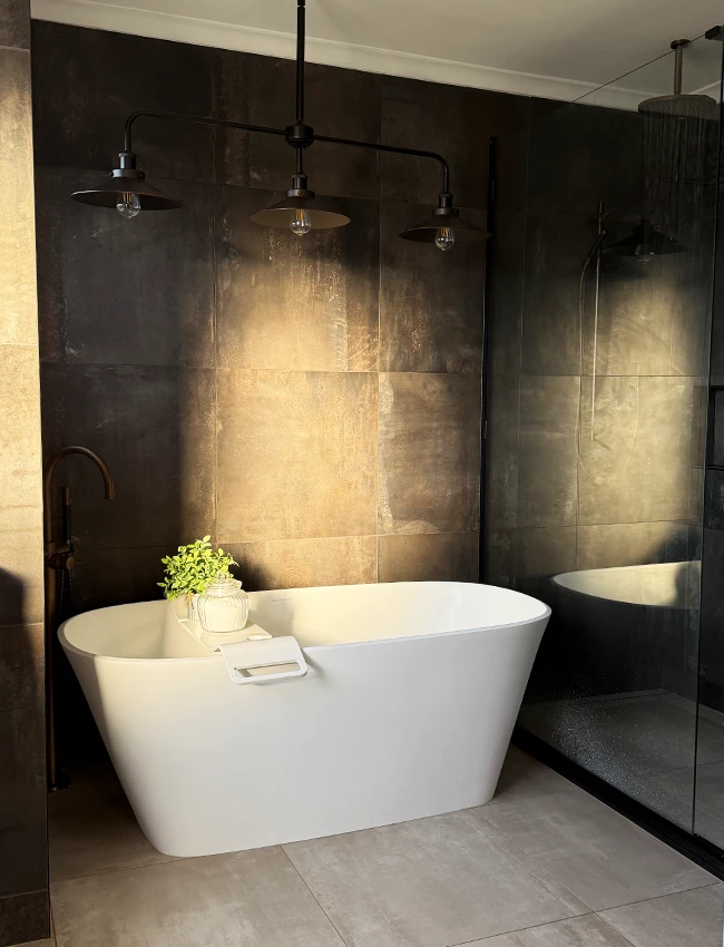 A modern bathroom renovation with new bath install and dark tiling in Papamoa home